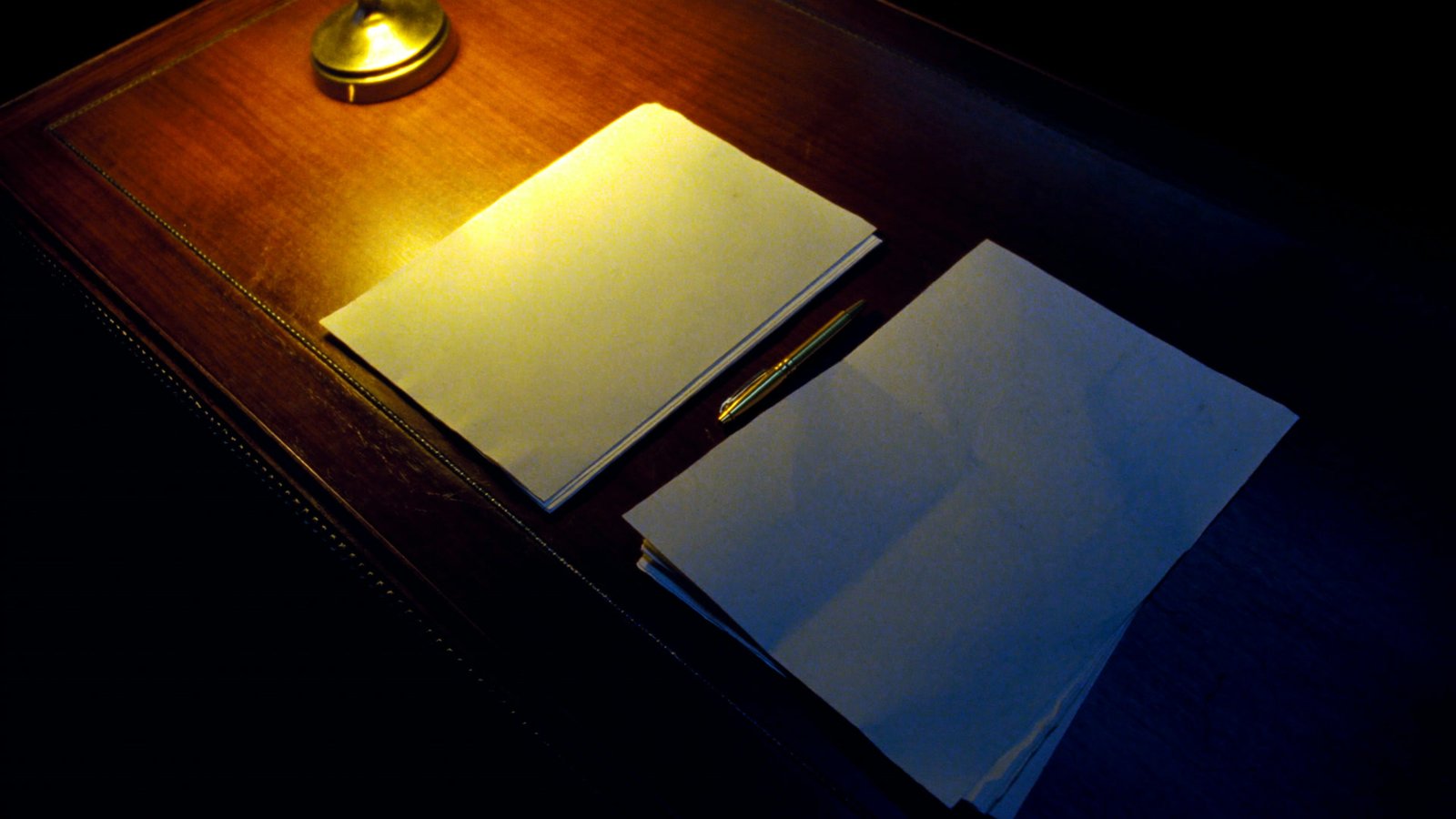Documentos e contas sobre uma mesa escura sob um foco de luz quente